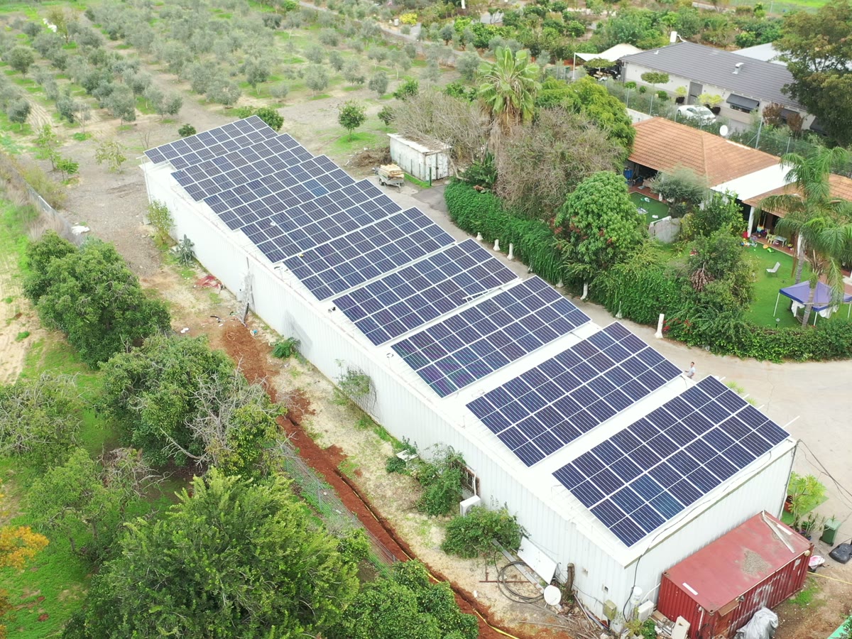 Vista aérea de un sistema solar sobre un galpón junto a quintas y campo abierto