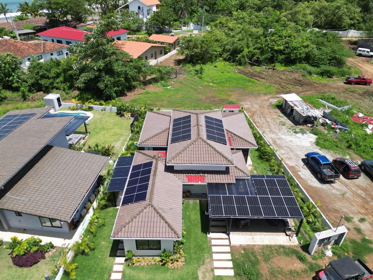 Vista aérea de una casa con paneles solares en el techo y una pileta en el jardín